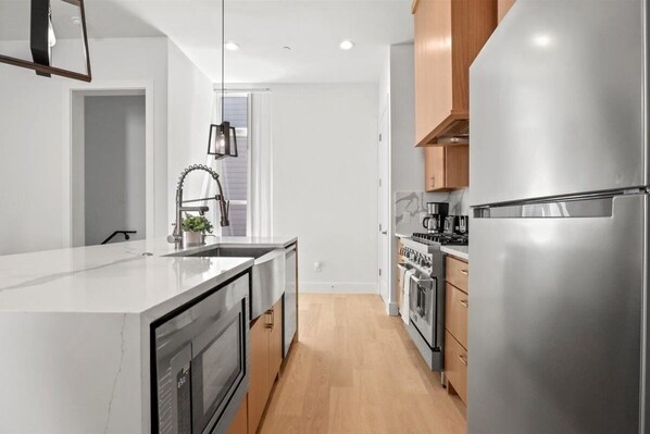 A modern kitchen with a central island, stainless steel appliances, and wooden cabinets.