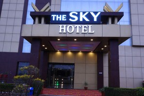 The Sky -hotellin ulkoasu: selkeä kyltti, lasinen sisäänkäynti ja punainen matto, joka johtaa oville.