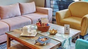 Ein Zimmer mit einer Couch, einem Sessel und einem Tisch mit Tee und Snacks auf einem Tablett.