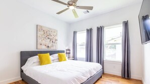 A bedroom with a bed, a ceiling fan, a window with curtains, and a wall-mounted artwork. - 111 Lavish Bungalow 1753! Medical Center, Stadiums (Houston)