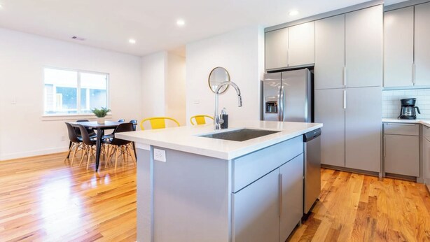 A modern kitchen with a central island, stainless steel appliances, and a dining area with chairs. - 111 Lavish Bungalow 1753! Medical Center, Stadiums (Houston)