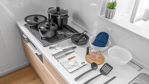 A modern kitchen with a stove, pots, pans, utensils, and a sink. - BEAR CUB HOTEL (Asahikawa)