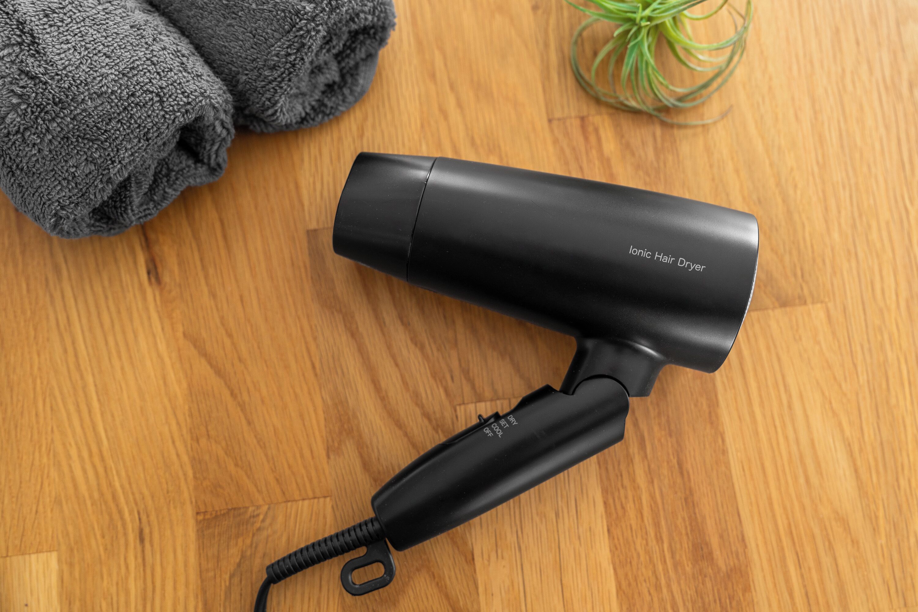 A black ionic hair dryer on a wooden surface.