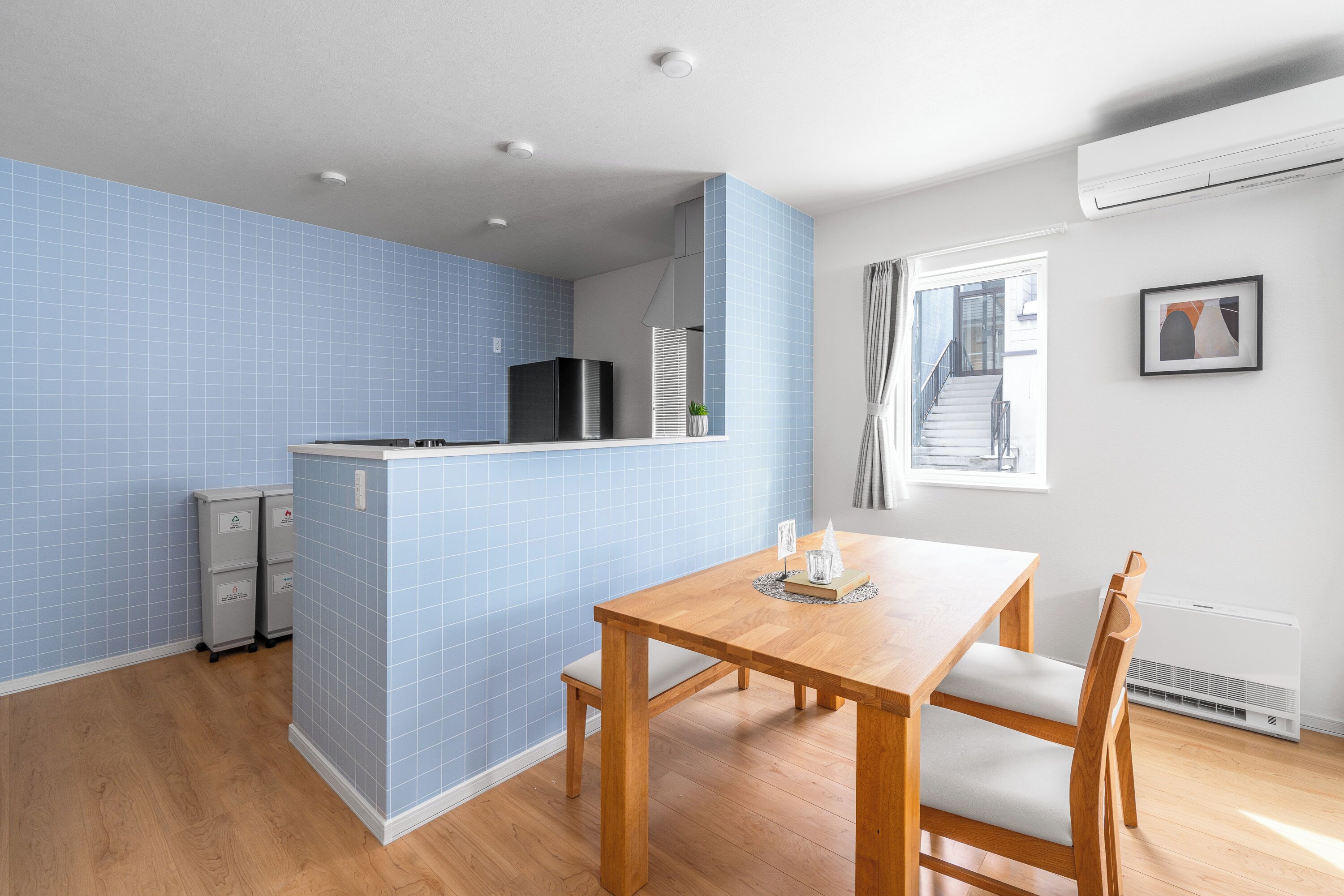 Una cocina compacta con azulejos azules, una mesa de comedor de madera y un refrigerador.