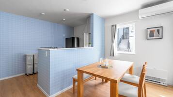 Una cocina compacta con azulejos azules, una mesa de comedor de madera y un refrigerador.