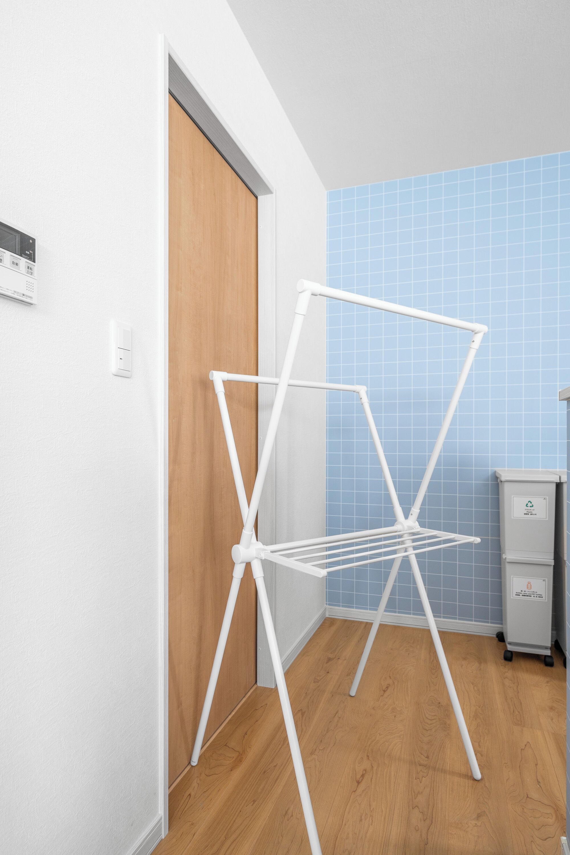 Un estante metálico blanco en un pasillo con puerta de madera y pared con azulejos azules.