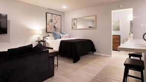 A modern bedroom with a bed, bedside table, lamp, and artwork on the walls. - Montrose Dazzle Studio, Near Med Center (Houston)