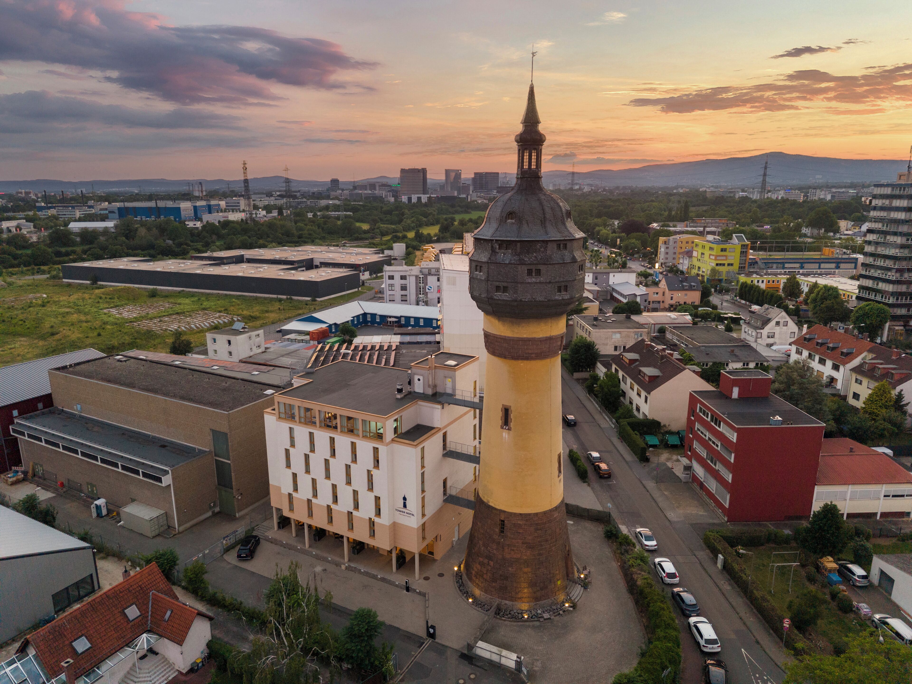 A tower with a clock, surrounded by buildings and a road.