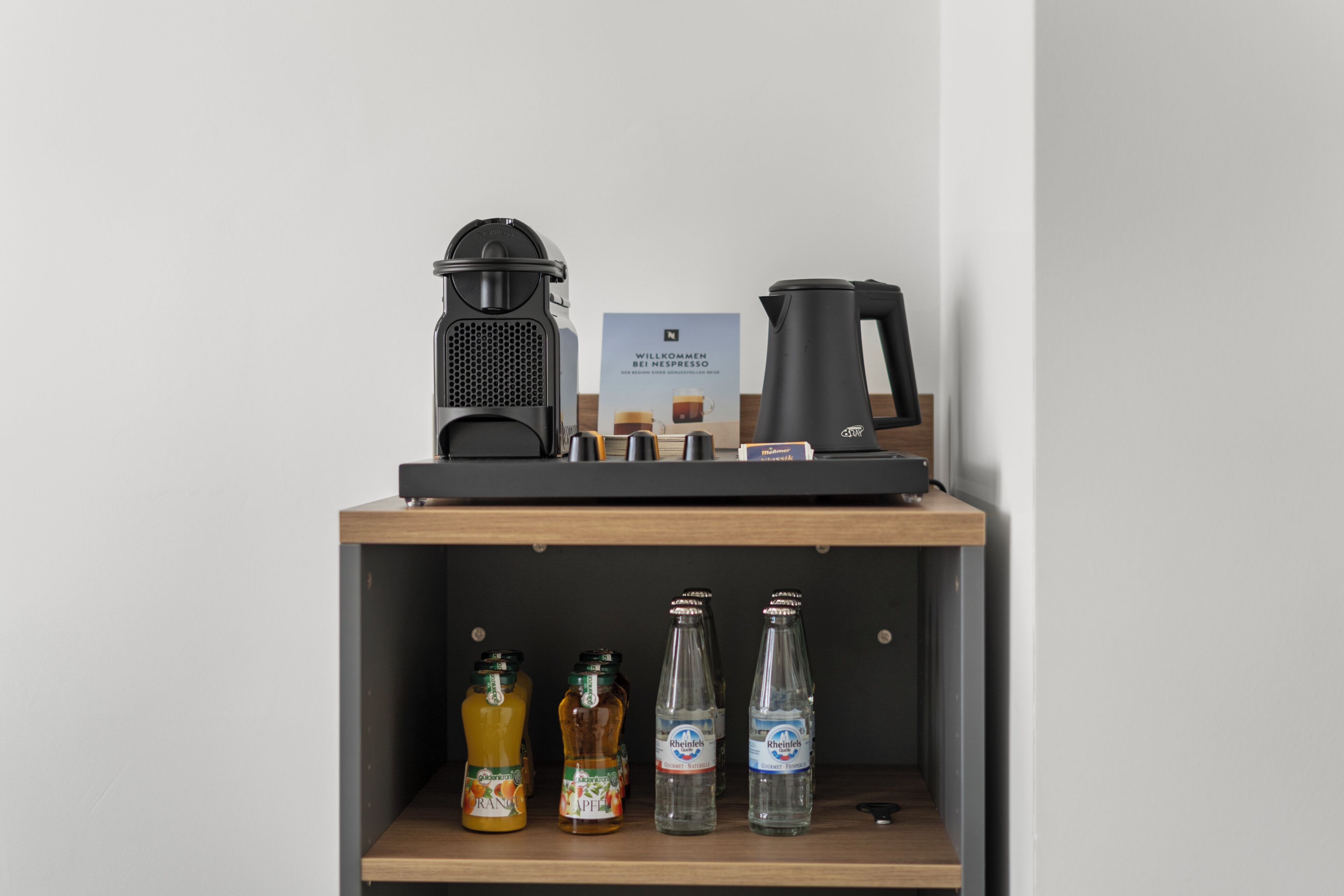 A coffee machine, a kettle, and a sign on a shelf with bottles.