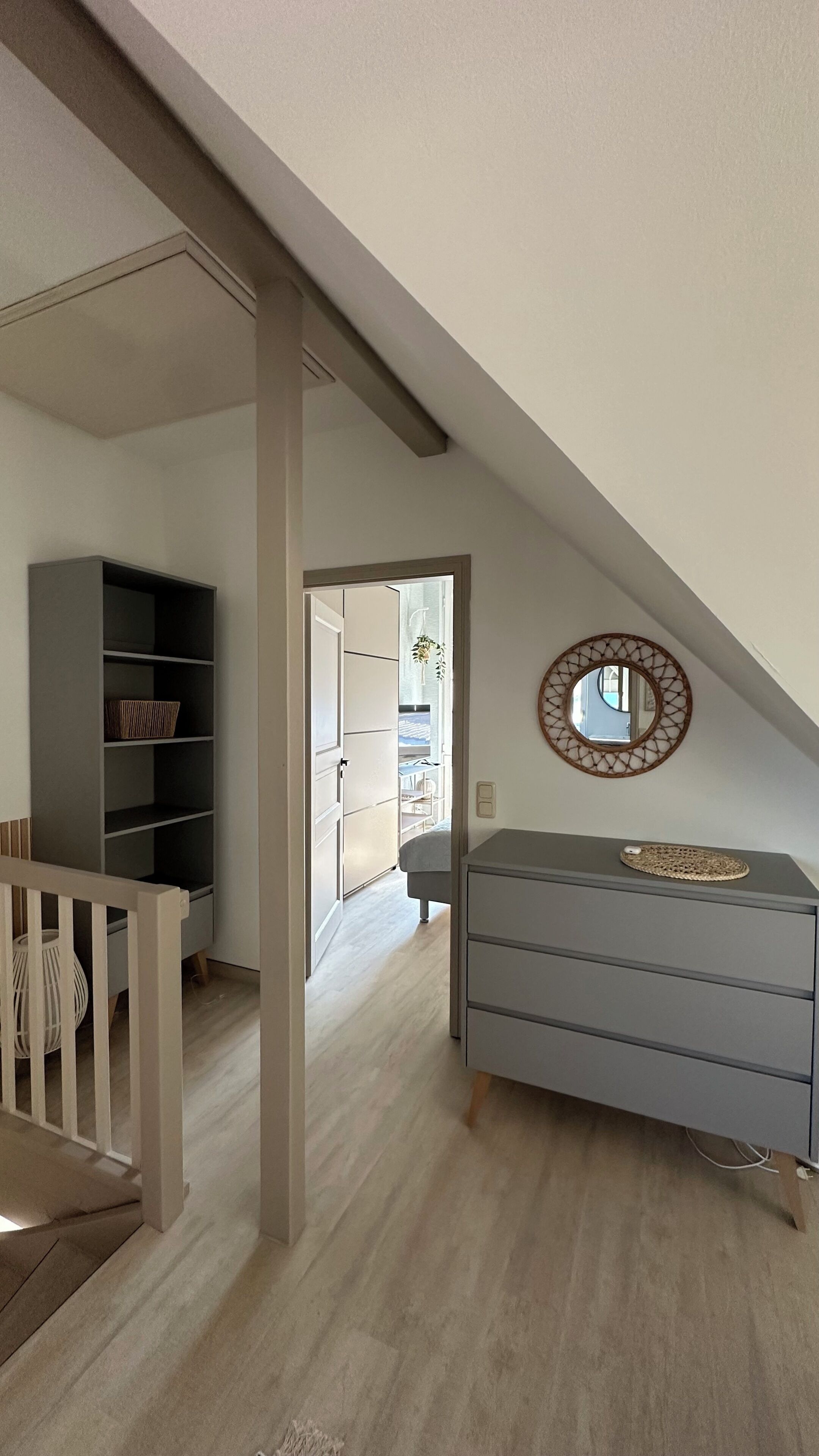 A room with a high ceiling, a built-in bookshelf, a dresser, and a mirror on the wall.