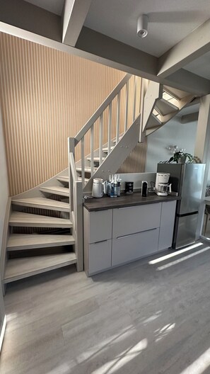 A modern kitchen with a built-in stove, a coffee maker, and a refrigerator. - Vacation home Sandbrise on the Baltic Sea in Zingst (61sqm) for up to 4 people (Zingst)