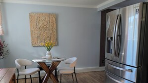 Eine moderne Küche mit Edelstahlkühlschrank, Holzboden und Essbereich mit Glastisch und Stühlen.