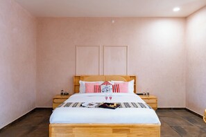 A neatly made bed with a wooden headboard, two bedside tables with lamps, and a wall-mounted light fixture.