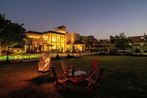 A building with a pool, outdoor seating, and a fire pit. - ELIVAAS Tuscan 5BHK Villa with Pvt Pool  (Pushkar)