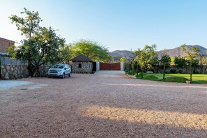 A gravel driveway leading to a stone house with a car parked on the left.