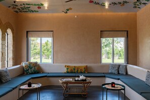 A cozy room with a curved sofa, two small tables, and a ceiling with floral decorations.