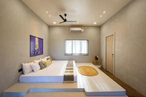 Un dormitori amb un llit, un ventilador de sostre, un aparell d'aire condicionat, una finestra amb cortines i una porta.