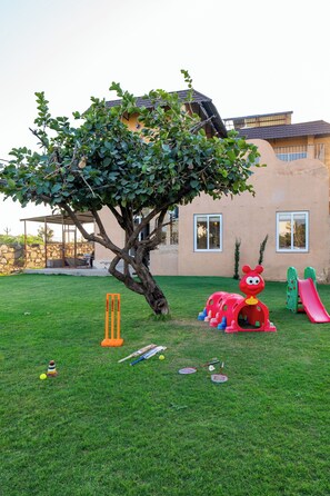 A tree in a backyard with a house in the background.