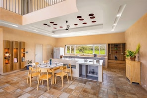 A spacious kitchen with a central island, wooden cabinetry, and a large window offering a view of the outdoors. - ELIVAAS Tuscan 5BHK Villa with Pvt Pool  (Pushkar)