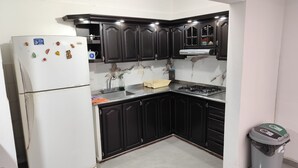 A kitchen with dark cabinets, a white refrigerator, a sink, and a stove. - Beautiful house in Cartago Valle (Cartago)