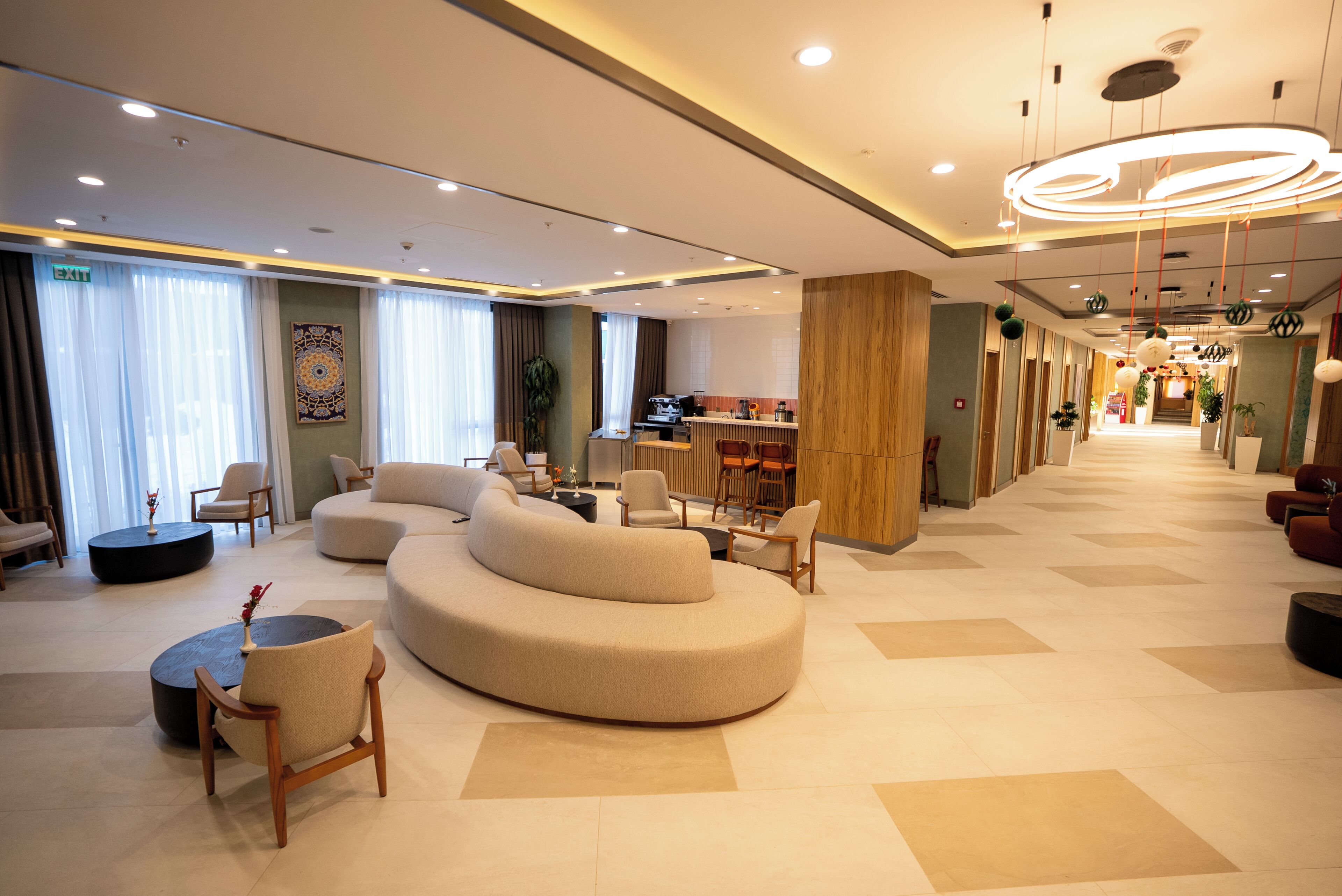 A modern hotel lobby with a curved sofa, seating area, and a bar.