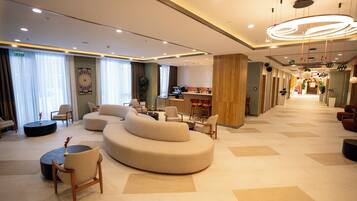 A modern hotel lobby with a curved sofa, seating area, and a bar.
