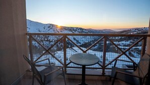 Un balcón con mesa y sillas, con vista a un paisaje nevado y montañas.