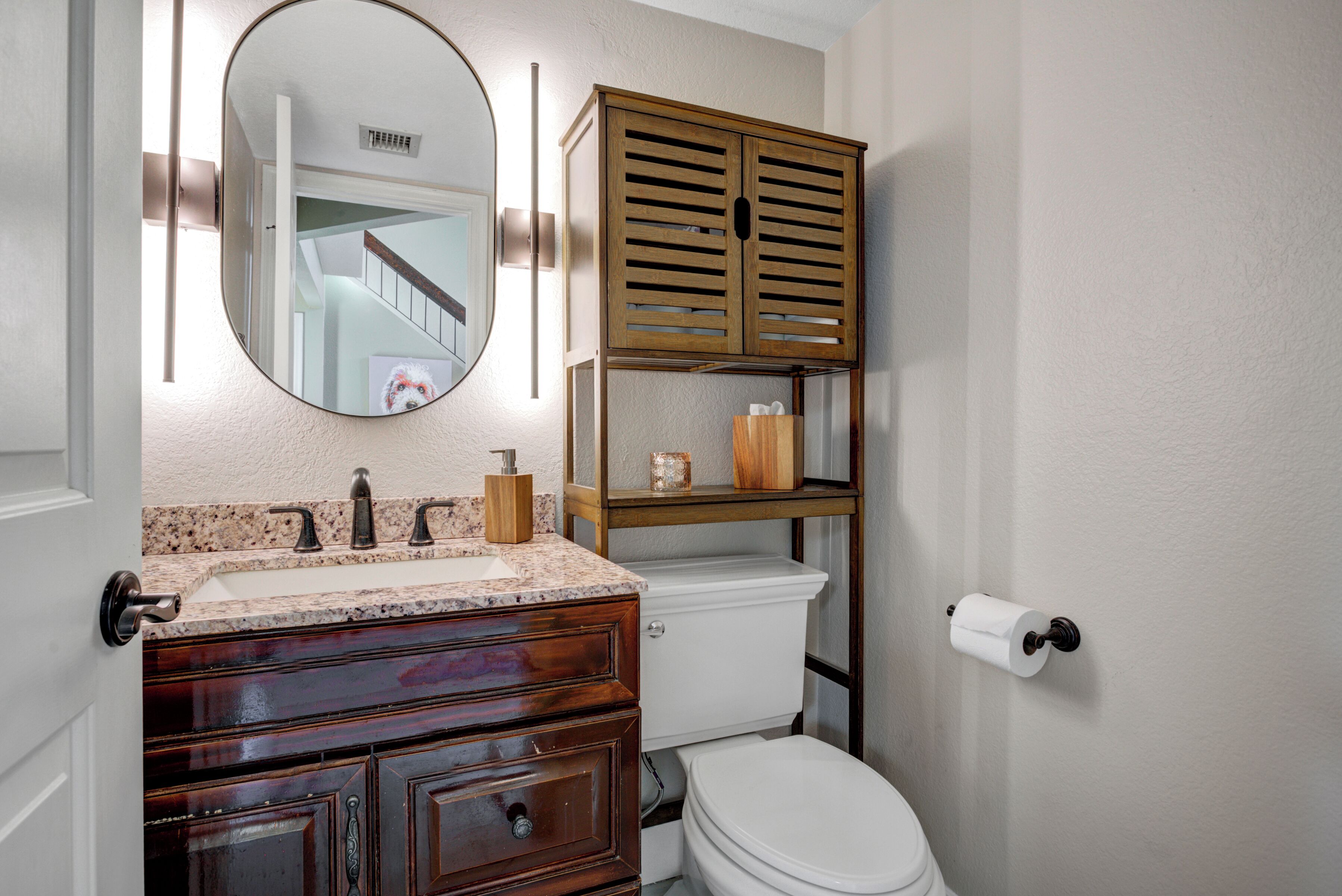 Un baño con un armario de madera, un lavabo, un inodoro y un espejo.