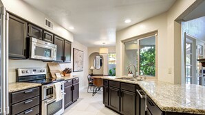 A modern kitchen with stainless steel appliances, dark cabinetry, and a large island with a sink. - Bright Phoenix Oasis w/Private Pool & Mtn Views (Phoenix)