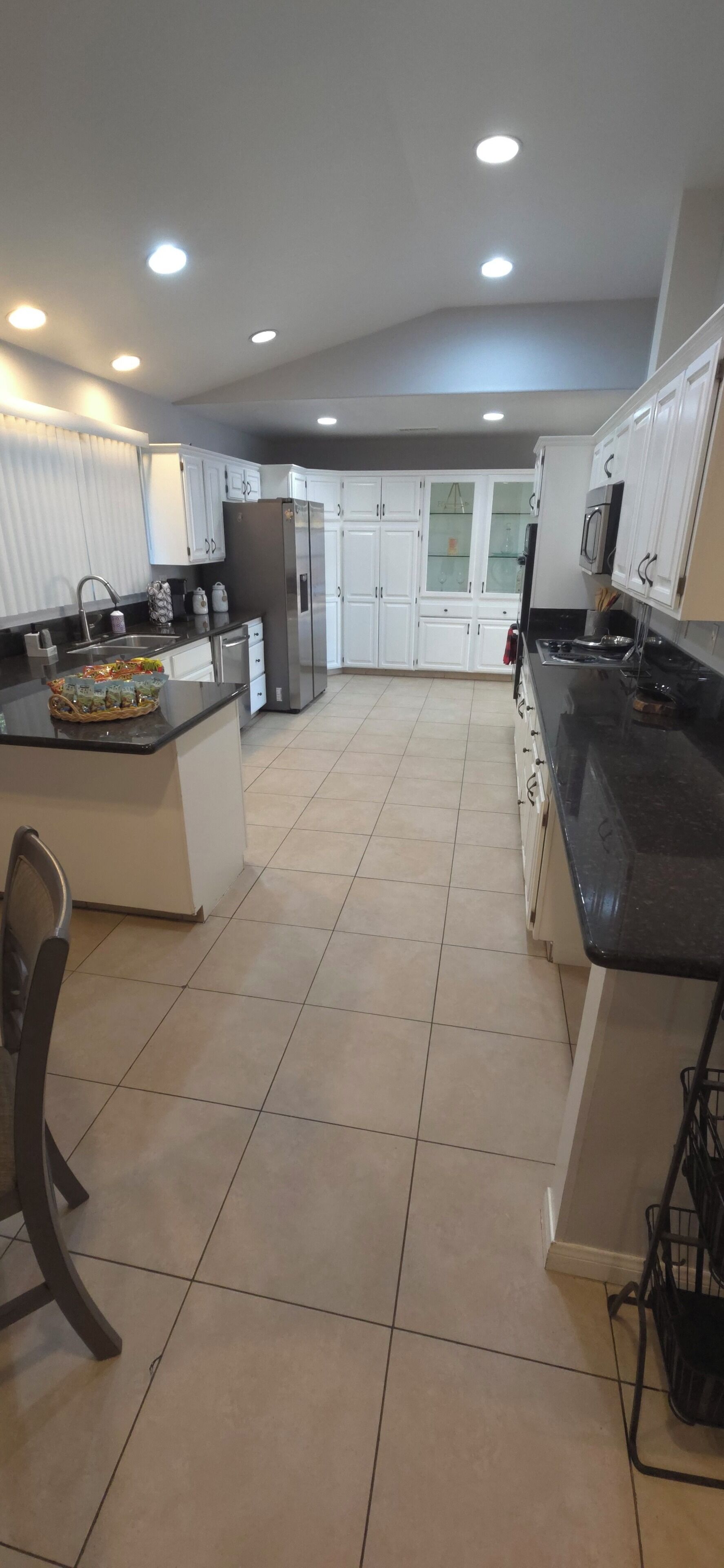 A modern kitchen with white cabinets, a black countertop, and a tiled floor.