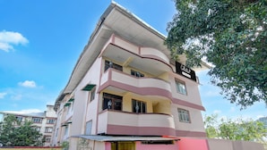 Un immeuble à plusieurs étages doté de balcons, d’une entrée sécurisée et surplombant un ciel dégagé.