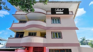 Un immeuble à plusieurs étages doté de balcons, une enseigne indiquant « Service aux entreprises » et un ciel dégagé.