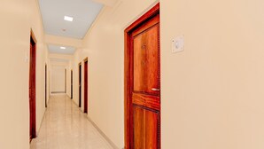 Un couloir d’hôtel avec des portes en bois, un sol carrelé et un mur de couleur claire.