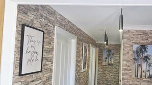 A hallway with stone walls, framed artwork, and pendant lighting.