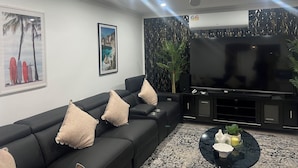A modern living room with a black sofa, a flat-screen TV, and decorative wall art.