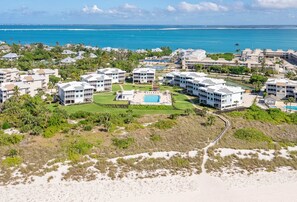A resort with multiple buildings, a central pool, and a beach view.
