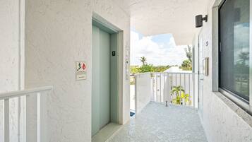 A corridor with a door, a balcony with a railing, and a window.