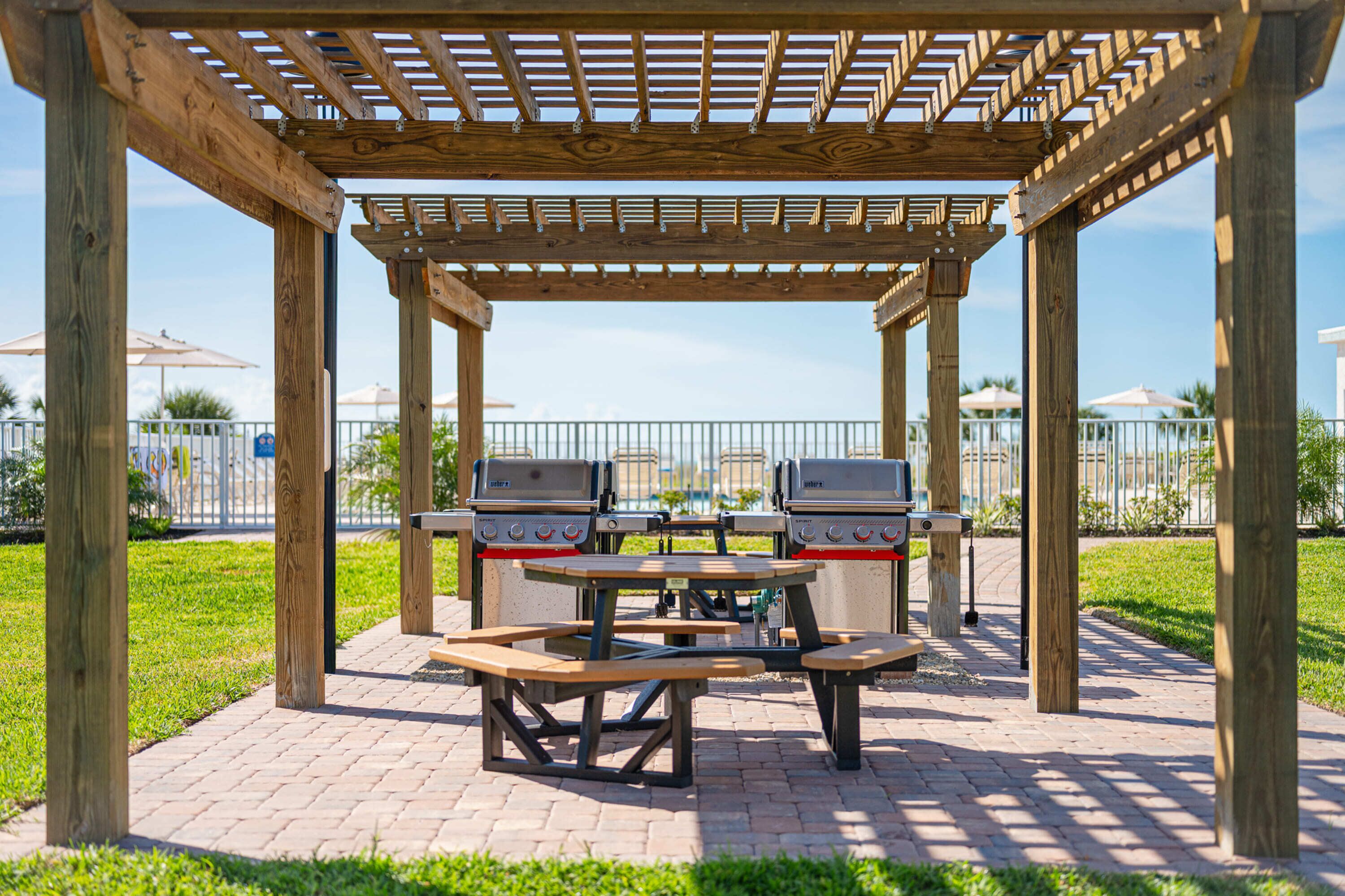 Un kiosque en bois avec des tables de pique-nique et des barbecues.