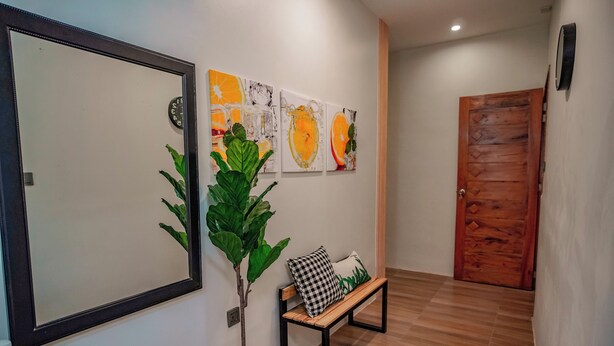 Un pasillo con un banco de madera, una planta en maceta y obras de arte en la pared.