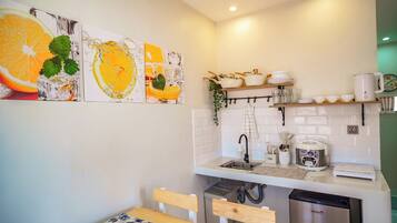 A modern kitchen with white tiles, a sink, a coffee maker, and a dishwasher.