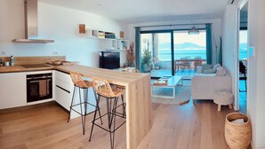 Una cocina moderna con una isla central, taburetes de bar y un comedor con vistas.