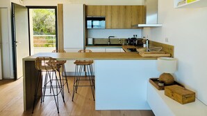 Una cocina moderna con armarios de madera, una isla central con taburetes y vistas a zonas verdes.