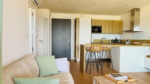 Una sala moderna con sofá, una mesa de centro y una zona de cocina con un taburete de bar.