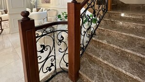 Una gran escala de marbre amb baranes metàl·liques ornamentals, que condueix a un pis superior ben il·luminat.