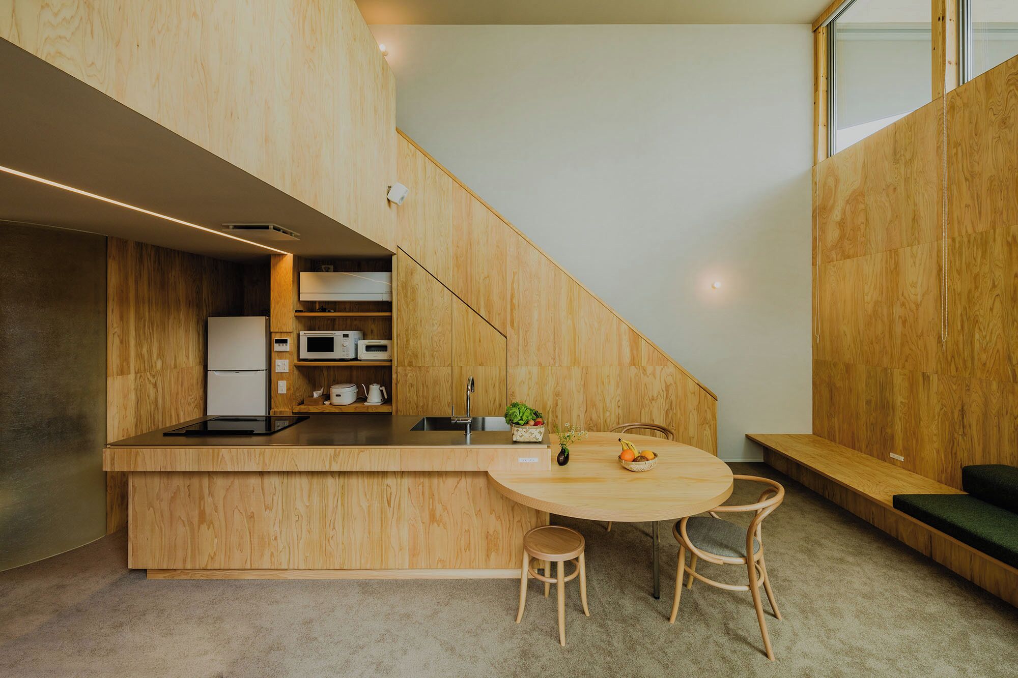 A modern kitchen with wooden cabinetry, a built-in microwave, and a dining area with a round table and two chairs.