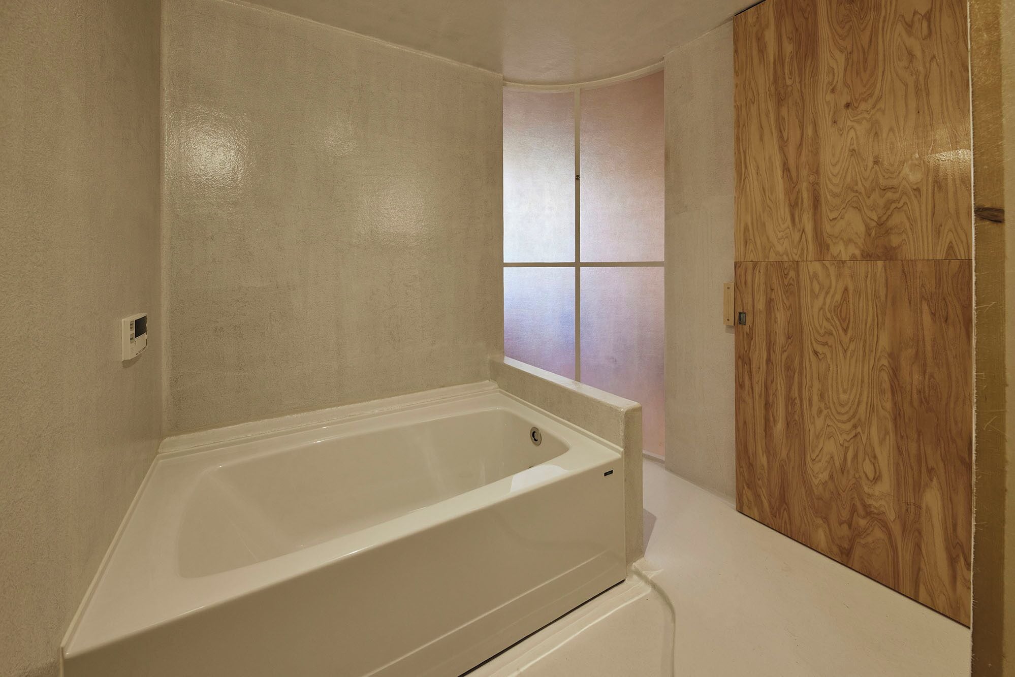 Un bagno con una vasca, un armadio in legno e una finestra con vetro satinato.