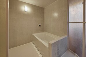 Un baño con bañera, zona de ducha y panel de control en la pared.