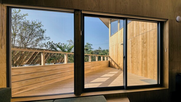 A modern interior with large sliding glass doors, a wooden deck outside, and a seating area with a bench and a small table. - SANU 2nd Home Ichinomiya 2nd (Ichinomiya)