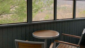 Una habitación con un ventanal grande, una mesa redonda y dos sillas.