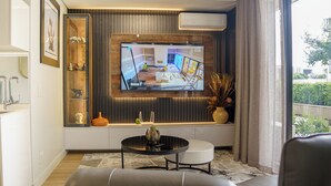 Ein modernes Wohnzimmer mit einem Wand-Fernseher, einer Couch, einem Couchtisch und Dekorationselementen.